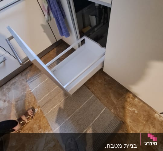 מגירה לבנה פתוחה במטבח עם ידיות מתכת